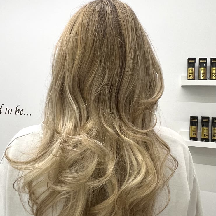 Light blonde balayage with soft waves, seen from behind