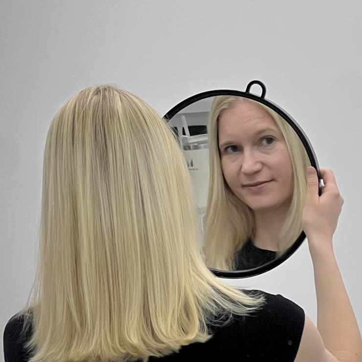 A client with a hand mirror and a platinum blonde bob
