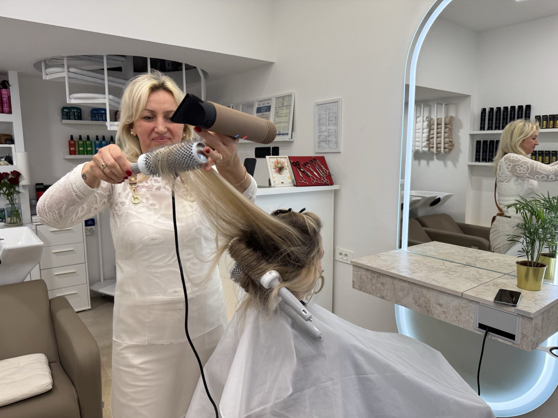 Inside TOP 13 – Halida styling a client's hair with a dryer and a round brush