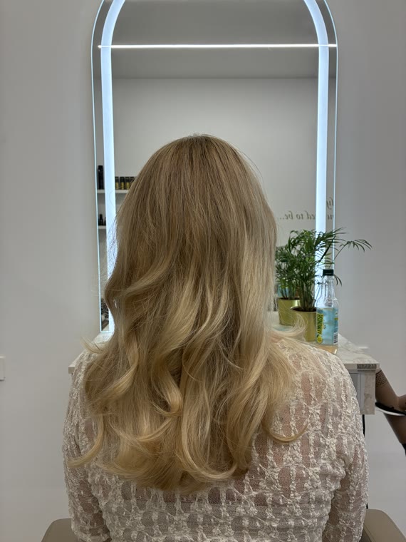 Long wavy hair coloured with balayage, the darker roots blending softly into blonde